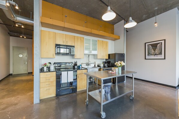 A modern kitchen with stainless steel appliances, wooden cabinets, and a central island.