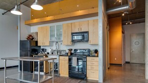 Een moderne keuken met roestvrijstalen apparatuur, houten kastjes en een karretje.