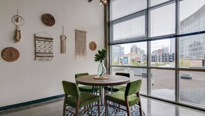 Een modern interieur met een ronde tafel, groene beklede stoelen en decoratieve wanddecoraties.