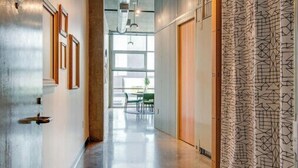 Een moderne hal met een gepolijst betonnen vloer, houten deuren en behang met een patroon.
