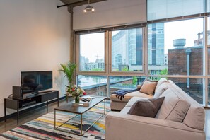 Relax in this stylish living room with a large flat-screen TV, comfortable sofa, and city views.