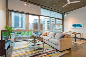 Relax in this stylish living room with a city view, featuring a sofa, coffee table, and dining area.