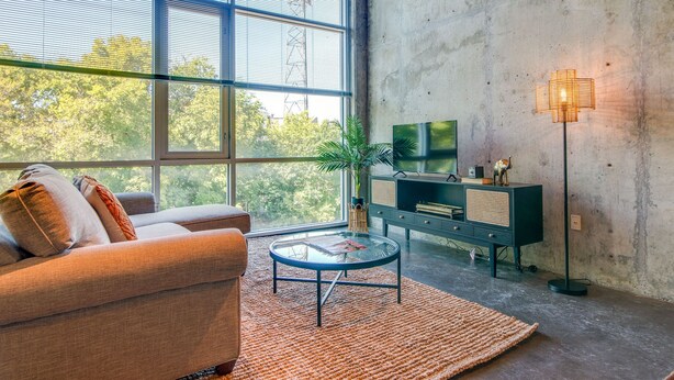A modern living room with a sofa, a glass coffee table, a TV, and a floor lamp. - Perfect Gulch Pad for Corporate Guests! (Nashville)