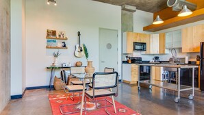 A modern kitchen with a dining area, featuring a dining table, chairs, a kitchen island, and a red rug. - Perfect Gulch Pad for Corporate Guests! (Nashville)