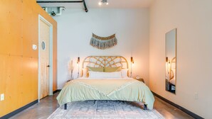A bedroom with a bed, a wall-mounted macrame piece, and a mirror. - Perfect Gulch Pad for Corporate Guests! (Nashville)