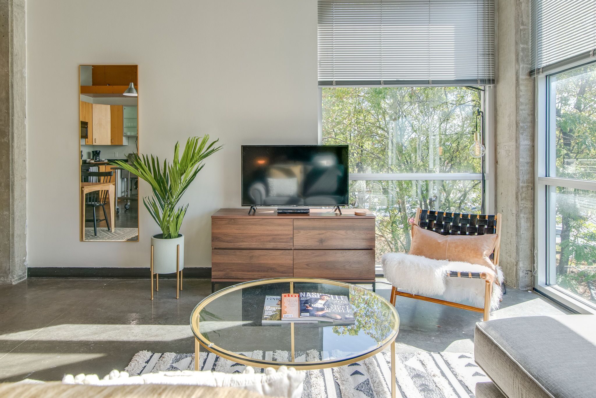 A modern living room with a glass coffee table, a wooden cabinet, a sofa, and a television.