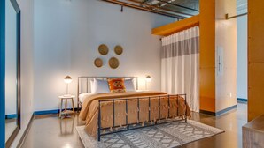 A modern bedroom with a metal bed frame, a round rug, and a bedside table with a lamp. - Spacious Condo in Downtown Gulch Neighborhood! (Nashville)