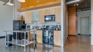 A modern kitchen with stainless steel appliances, wooden cabinets, and a cart. - Spacious Condo in Downtown Gulch Neighborhood! (Nashville)