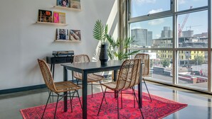 A dining area with a table, chairs, and a red rug. There are shelves with books and a plant. - Spacious Condo in Downtown Gulch Neighborhood! (Nashville)