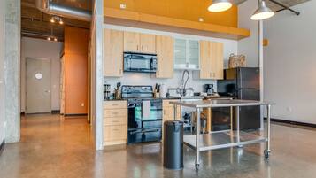 A modern kitchen with wooden cabinets, a stainless steel refrigerator, and a cart.