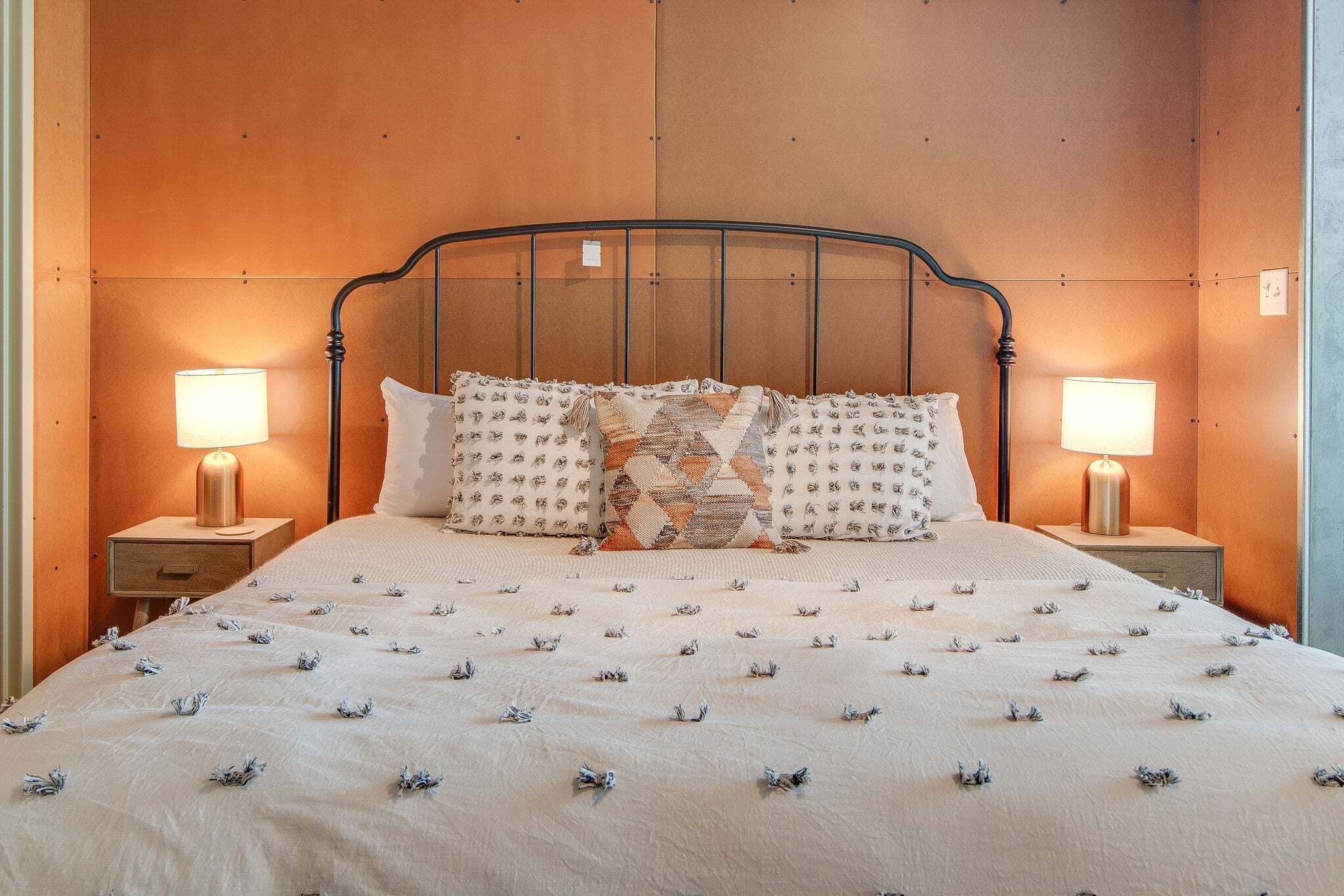 A bed with a patterned bedspread, two bedside lamps, and a headboard.