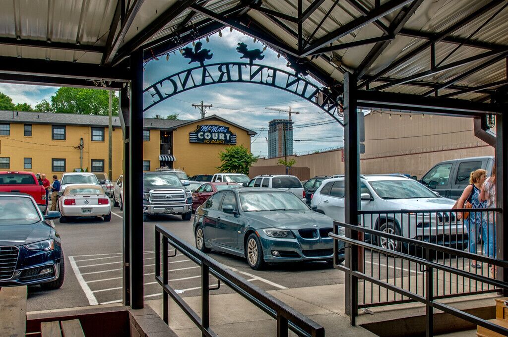 A parking area with a McMullen Court sign, multiple cars, and a building with a yellow facade.