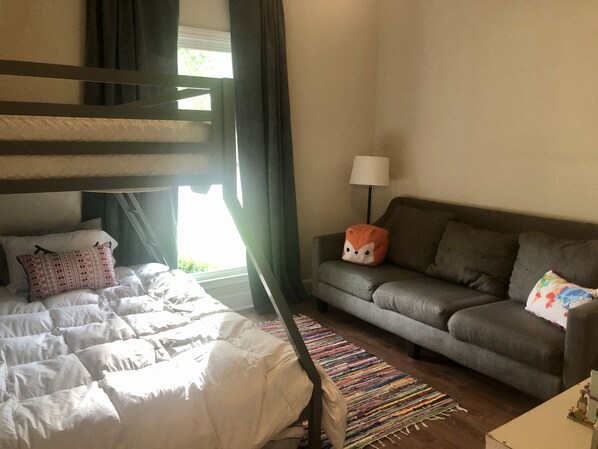 A bedroom with bunk beds, a grey sofa, a colorful rug, and a lamp. - Game Day Ready! (Tuscaloosa)