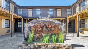 A courtyard with a stone fountain, wooden benches, and a staircase leading to a building with balconies. - 2BR Nashville Retreat 1.4 Mi to Broadway (Nashville)
