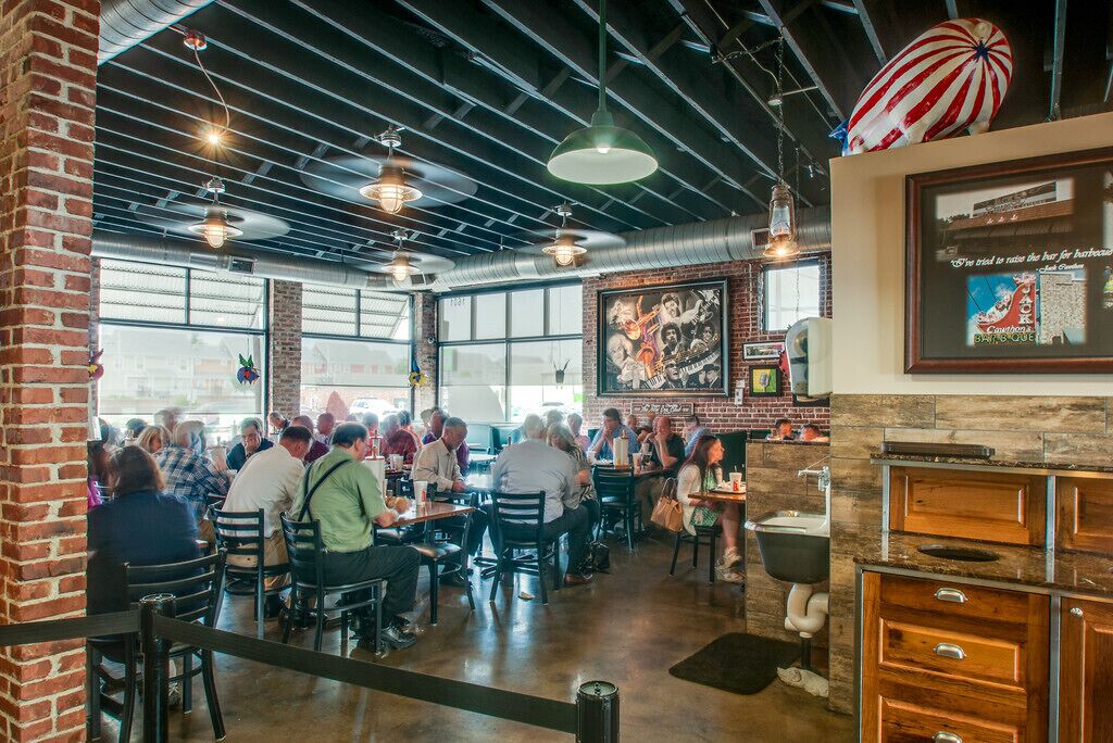 A restaurant with brick walls, large windows, and hanging pendant lights.