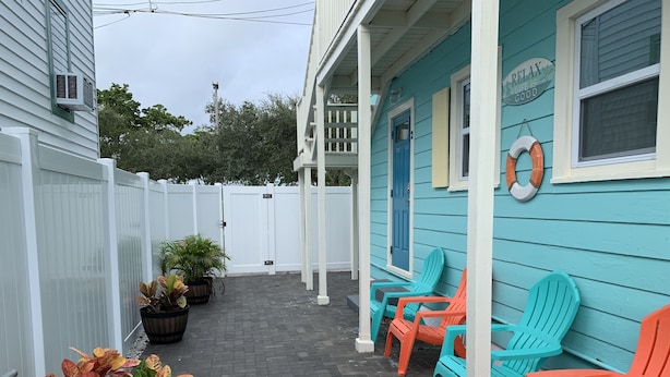 Eine Veranda mit Sitzgelegenheiten im Freien, einem weißen Zaun und Blumentöpfen.