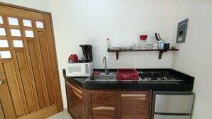 Cocina compacta con microondas, cafetera, lavabo y un refrigerador pequeño.