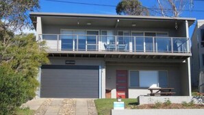 A two-story building with a garage, a balcony, and a small outdoor seating area.