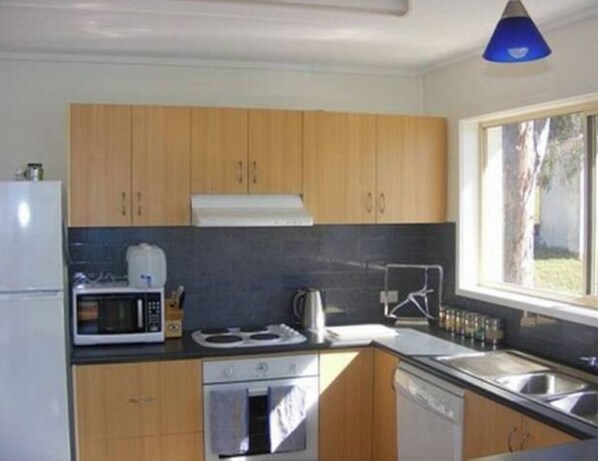 Una cocina moderna con armarios de madera, microondas, estufa y lavavajillas.