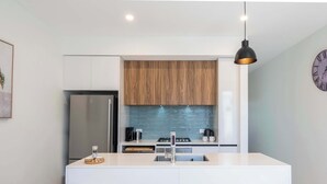 Una cocina moderna con una isla central, electrodomésticos de acero inoxidable y un protector contra salpicaduras de madera.