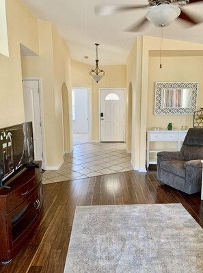 Relax in this stylish living room with a high ceiling, wooden floor, and comfortable armchair.