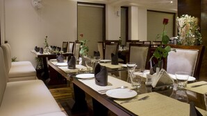 Un comedor con una mesa larga dispuesta para una comida, sillas y una planta decorativa.