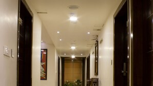 Un pasillo de hotel con suelo de mármol, puertas de madera y una zona de comedor con sillas y una mesa.