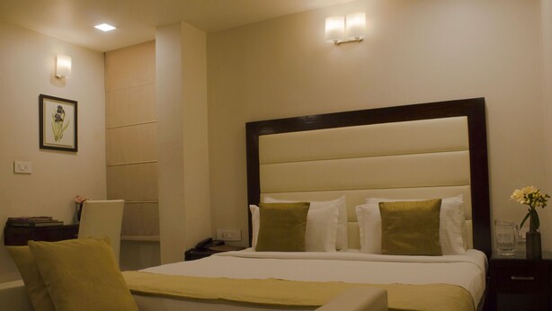 Una habitación de hotel con una cama, mesitas de noche, una silla y un velador.
