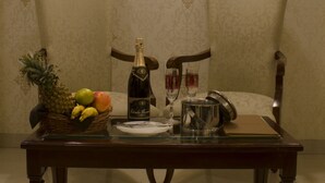 Una mesa de comedor con una botella de champán, una cesta de frutas y dos copas.