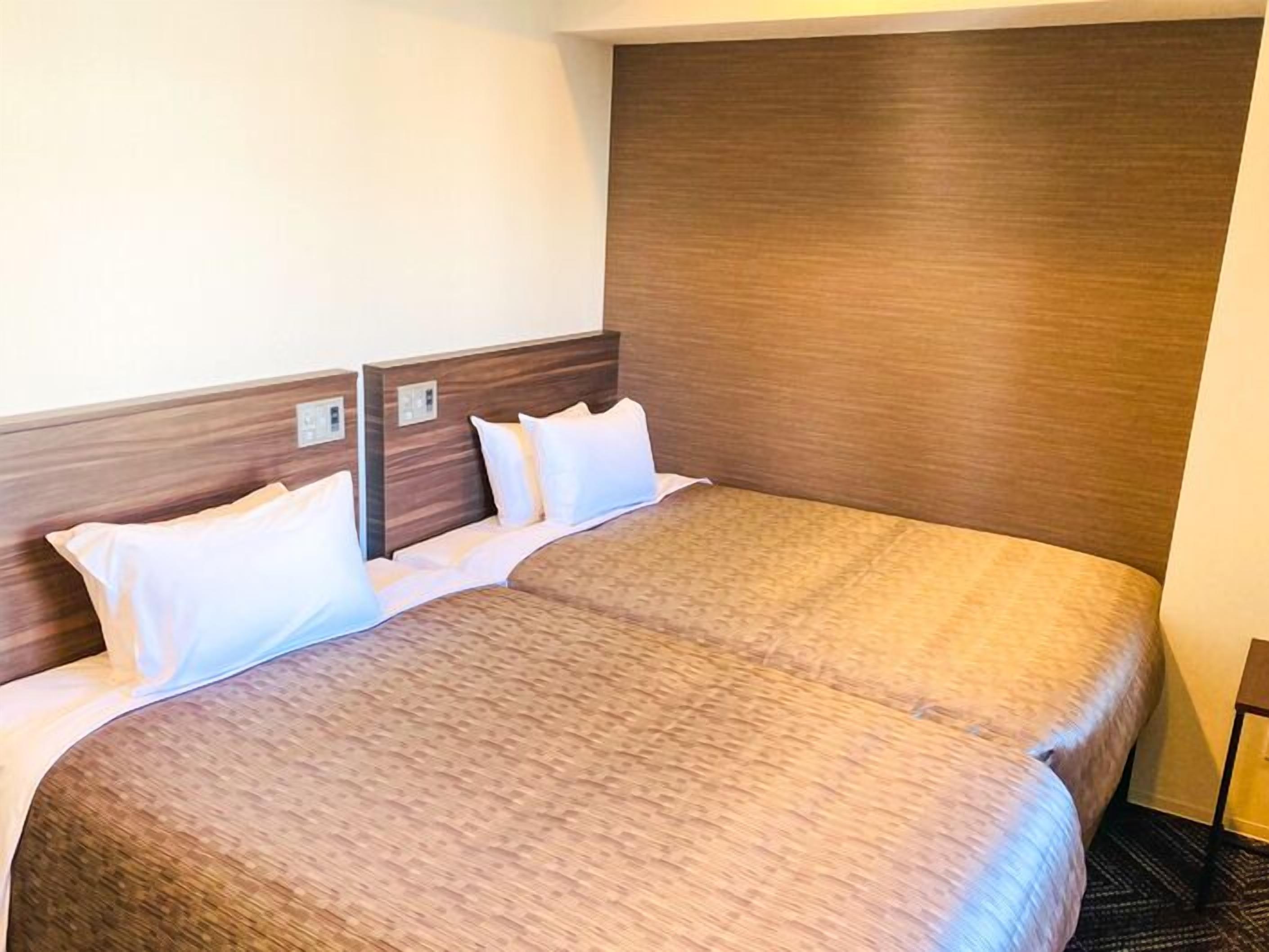 A double bed with a wooden headboard, white bedding, and a carpeted floor.