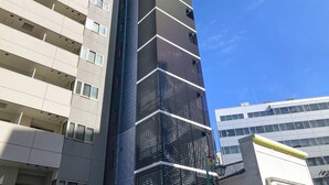 Ein hohes, modernes Gebäude mit einer markanten Schwarz-Weiß-Fassade, das eine Reihe von Balkonen und einen auffälligen Eingang aufweist.