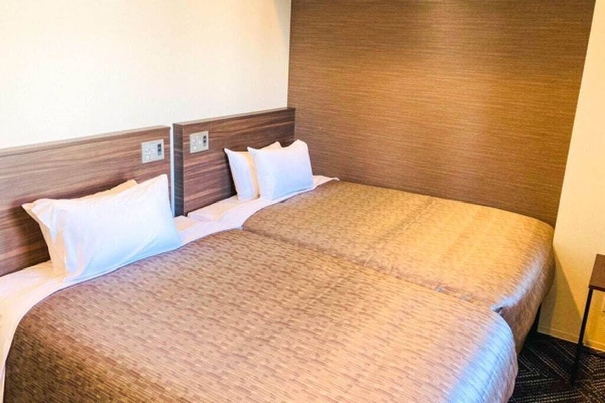 A hotel room with a large bed, wooden headboard, and white bedding.
