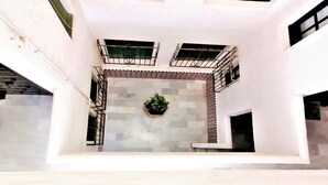Un edificio moderno con un patio central, que incluye una planta en maceta, paredes de azulejos y barandillas de metal en los balcones.