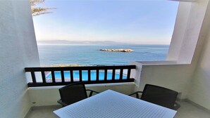 Un balcón con vista a la piscina, dos sillas y una mesa.
