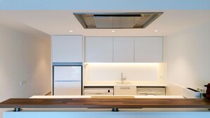 Una cocina moderna con armarios blancos, horno empotrado y lavavajillas.