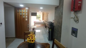 A hallway leading to a bedroom with a bed, a kitchen area, and a dining area with a table and chairs. - PALMAS DE CHAHUE C (581 SF) (Crucecita)