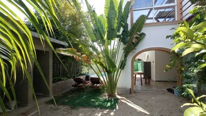 A courtyard with a green artificial turf, a wooden bench, and a potted plant. - PALMAS DE CHAHUE C (581 SF) (Crucecita)
