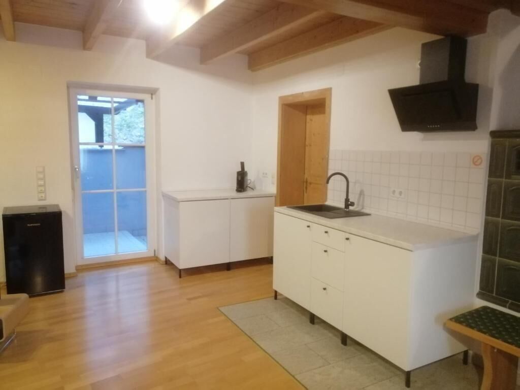A kitchen with white cabinets, a black sink, and a wooden ceiling.