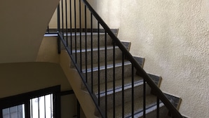 A staircase with black railings and beige walls.