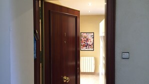 A wooden door with a brass handle, a framed picture on the wall, and a light switch.