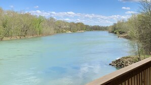 Eine Holzdar Terrasse mit Blick auf einen Fluss, dessen klares Wasser von Bäumen gesäumt ist.