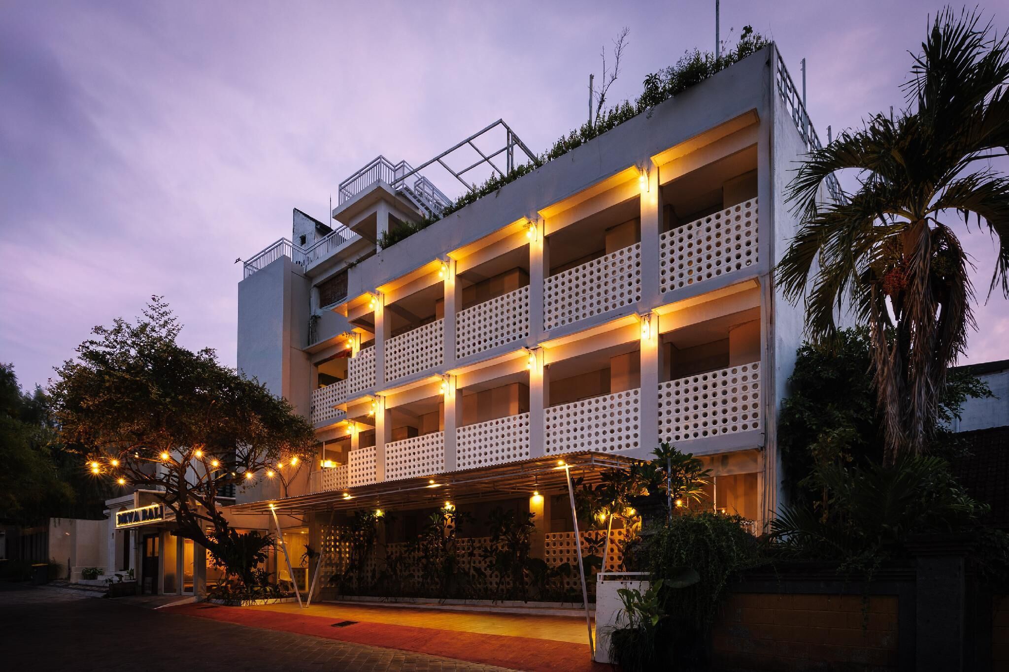A multi-story hotel with balconies, a covered entrance, and a red carpet.