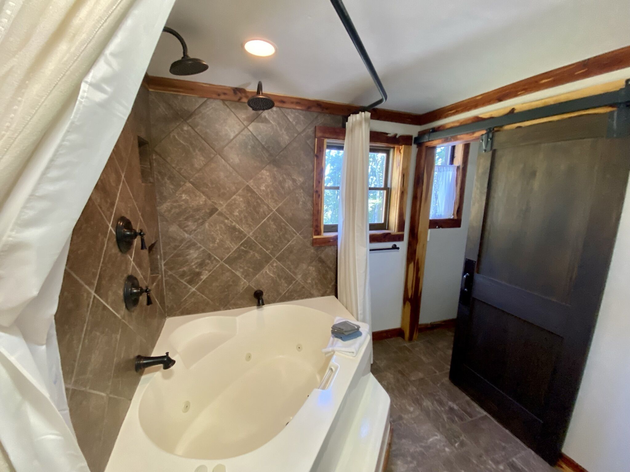 Une salle de bain avec une baignoire, une douche et une porte donnant sur une autre pièce.