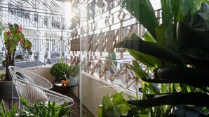 A balcony with a geometric metal fence, potted plants, and a white wicker chair. - The Note Dalat - Hostel (Xuan Huong - Da Lat)