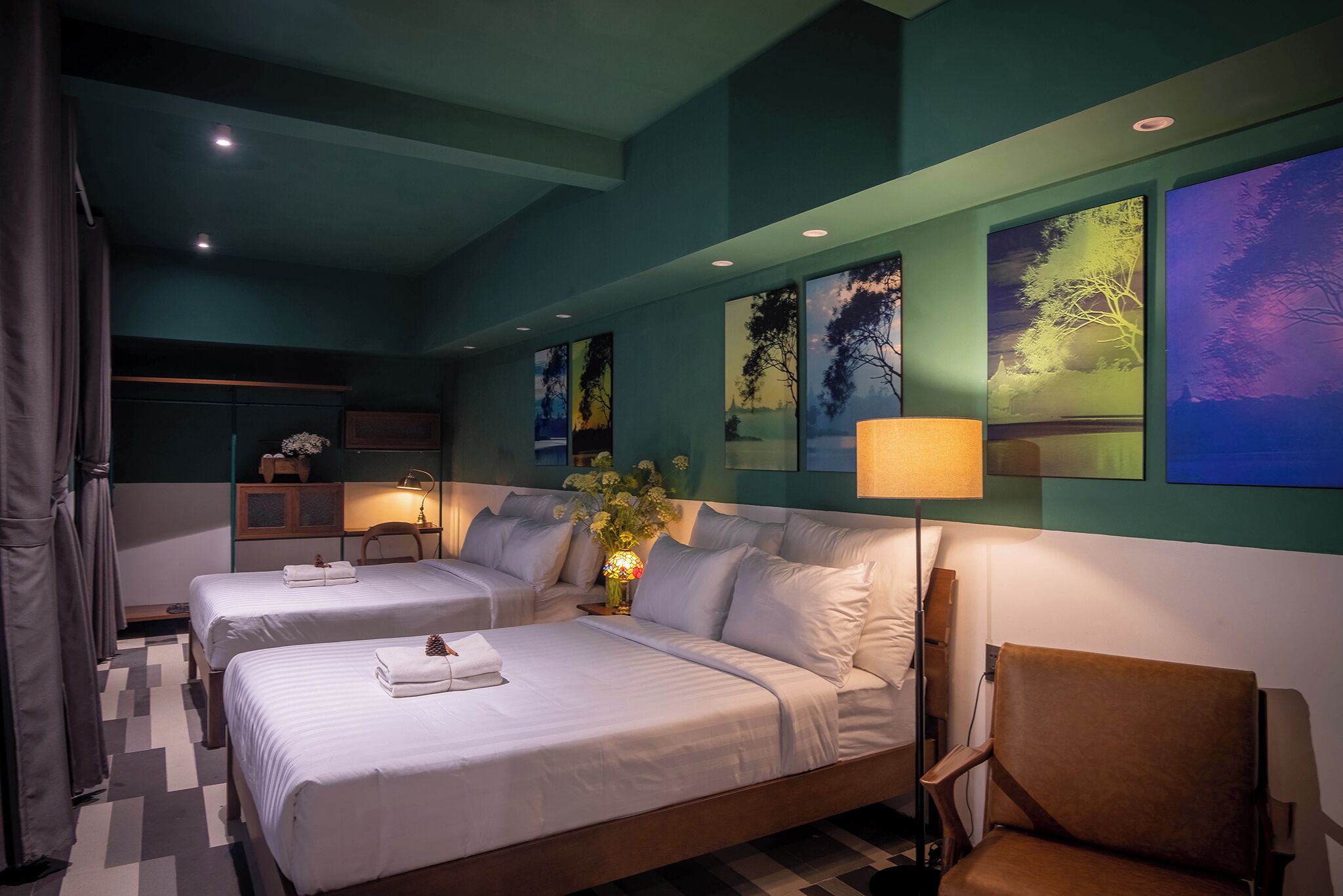 Habitación de hotel con dos camas, una silla, un escritorio y un florero con flores.