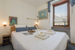 A neatly made bed with a tray of croissants, a book, and folded towels.