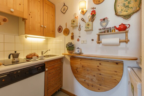 Una cocina con armarios de madera, una estufa, un fregadero y diversos utensilios de cocina y adornos en la pared.