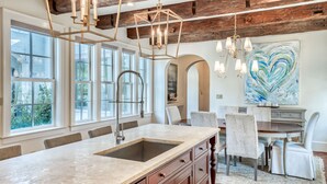 A kitchen with a large island, wooden beams, and a dining area with a table and chairs.