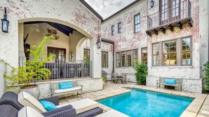 A pool area with outdoor seating and a brick building.