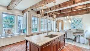 A spacious kitchen with a large island, wooden beams, and a view of the outdoors.